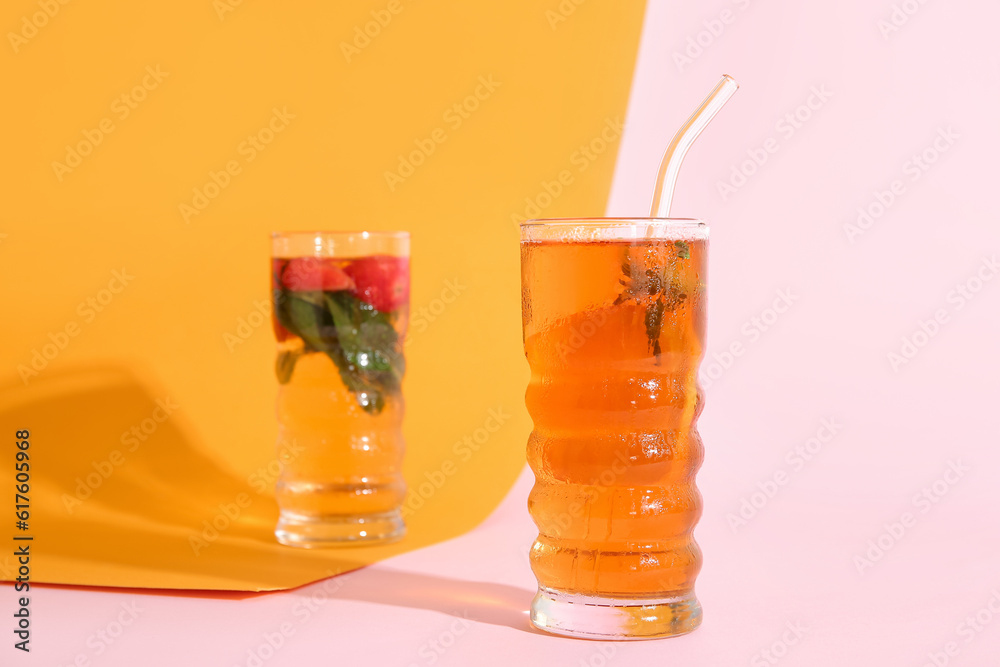 Glasses of ice tea with orange and strawberry on colorful background