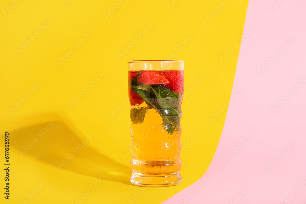 Glass of ice tea with strawberry and mint on colorful background