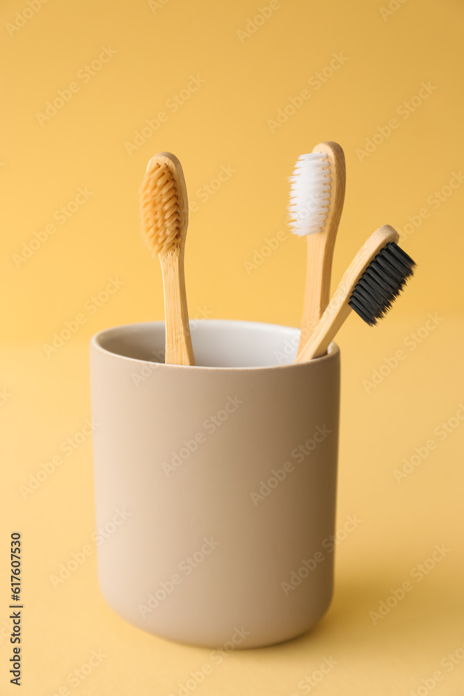 Bamboo tooth brushes in holder on beige background