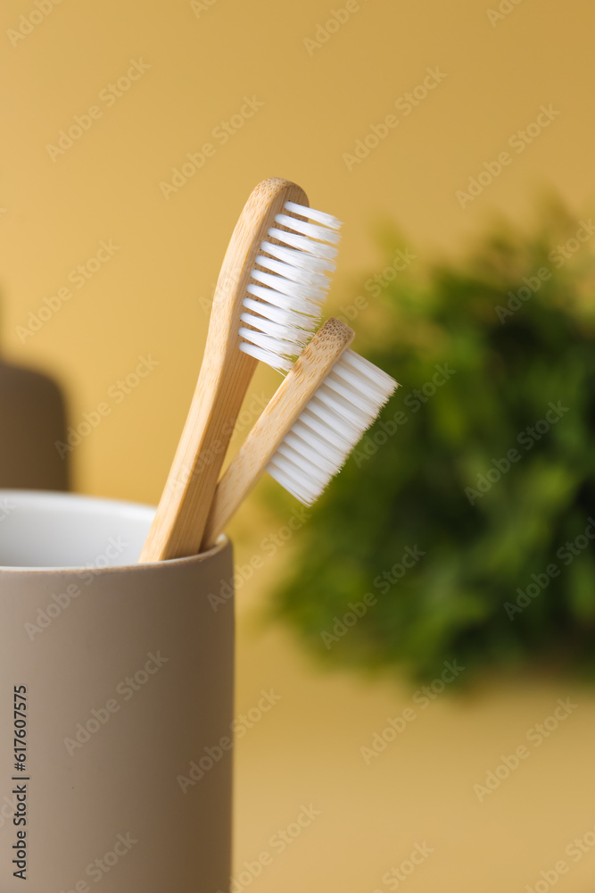 Bamboo tooth brushes in holder on beige background, closeup