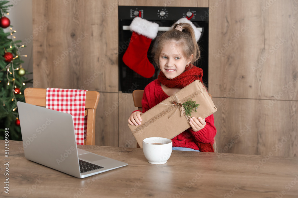 Cute little girl with Christmas gift in kitchen