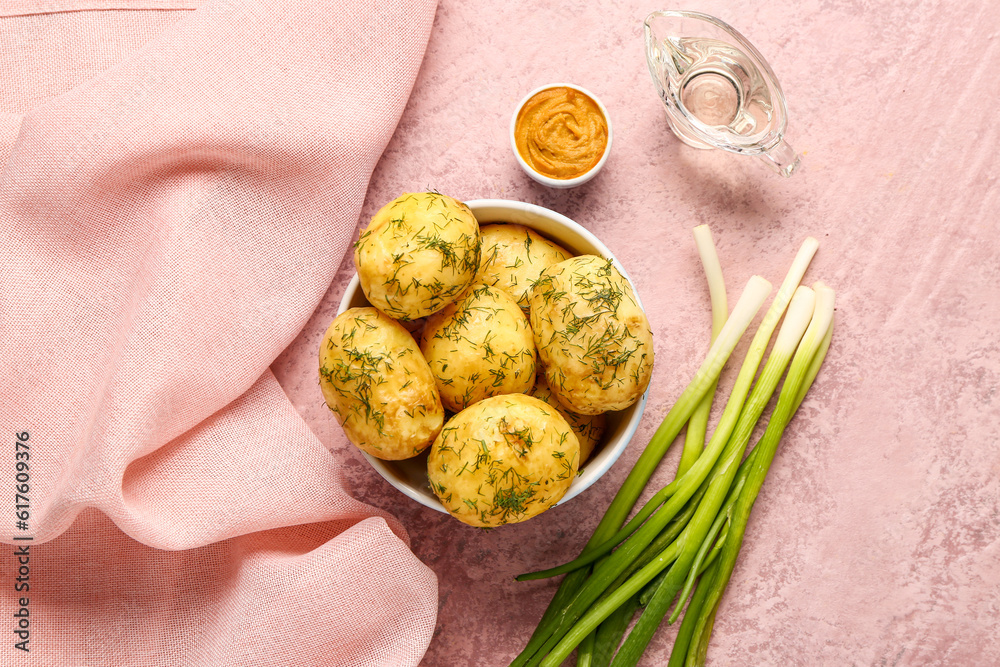 Bowl of boiled baby potatoes with dill and green onion on pink background