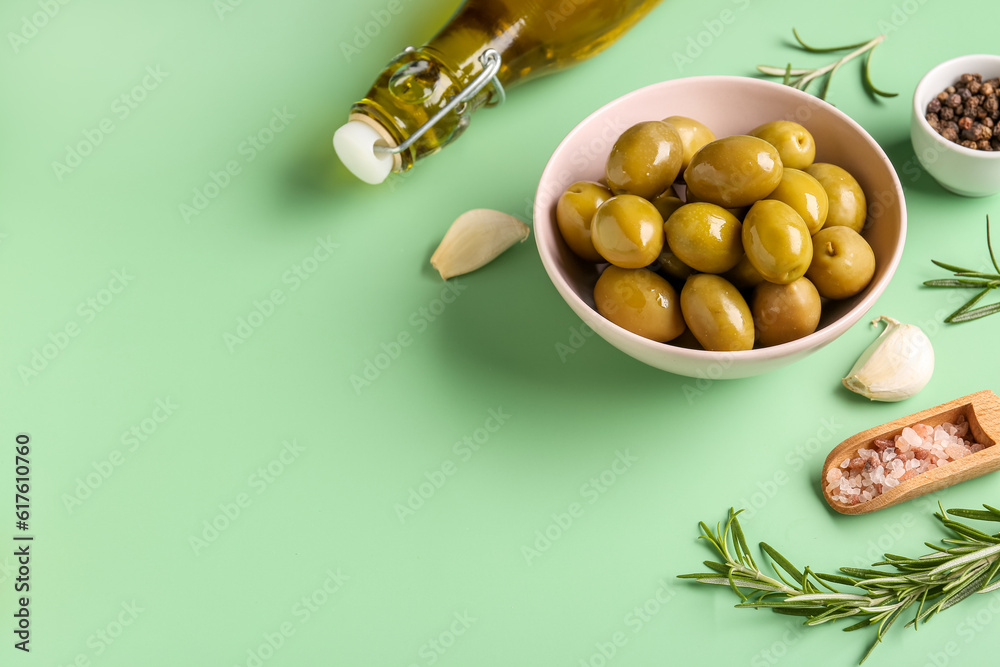 Bowl with ripe olives on green background