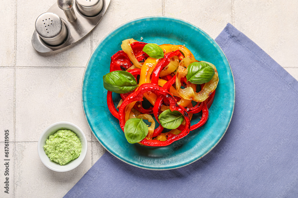 Plate with slices of tasty grilled peppers on white tile background