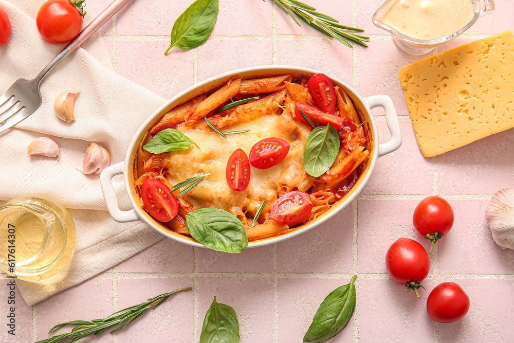 Baking dish of pasta with tomato sauce and cheese on pink tile background