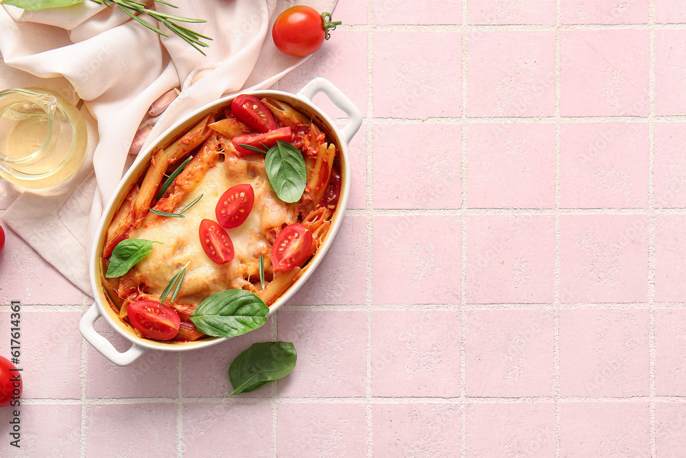 Baking dish of pasta with tomato sauce and cheese on pink tile background