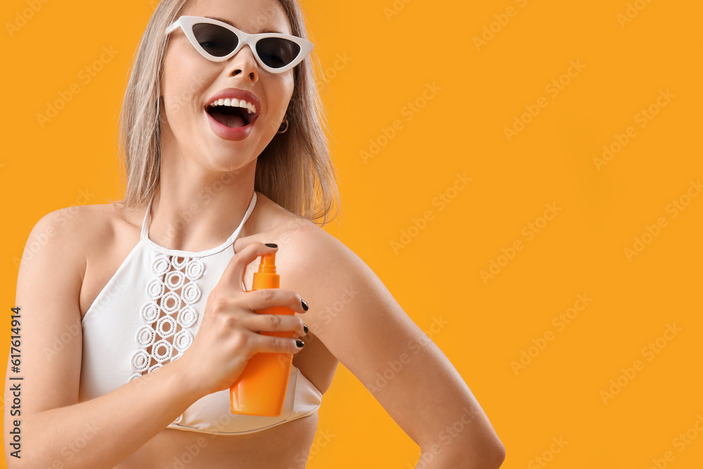 Young woman with sunscreen cream on yellow background