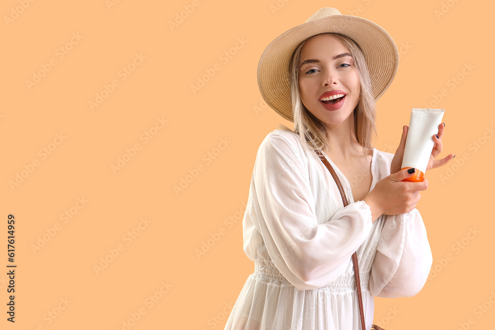 Young woman with sunscreen cream on beige background