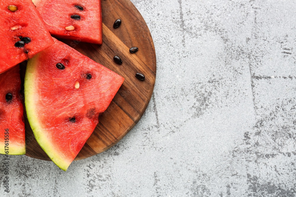 Board with pieces of fresh watermelon and seeds on grey background