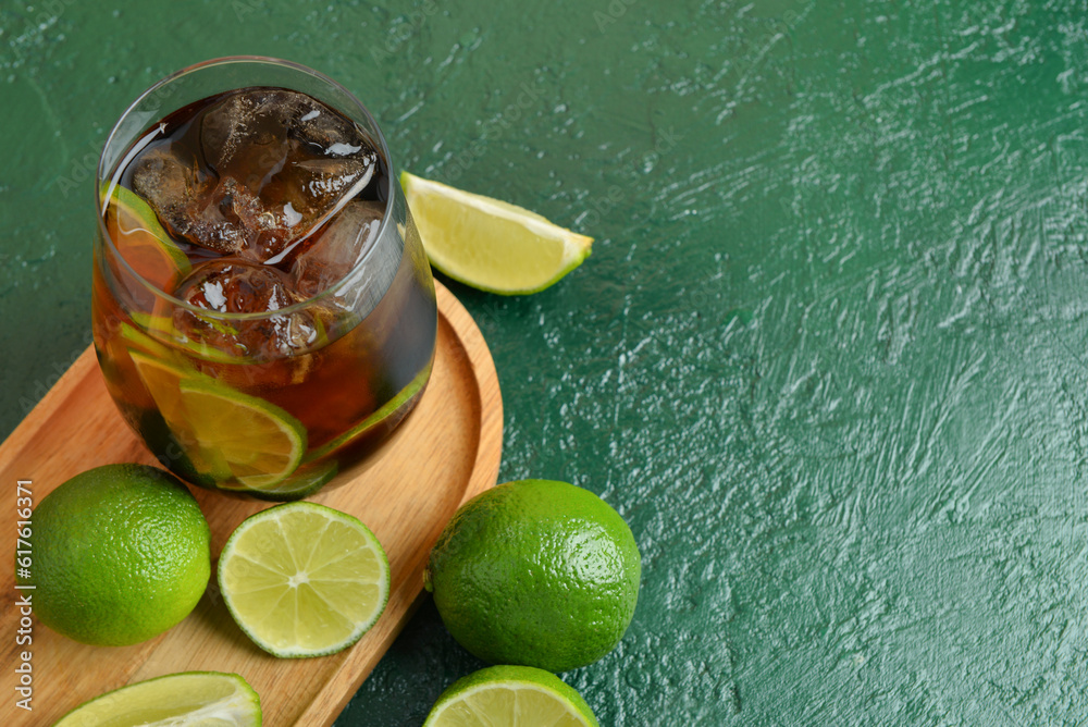 Glass of cold Cuba Libre cocktail on green background