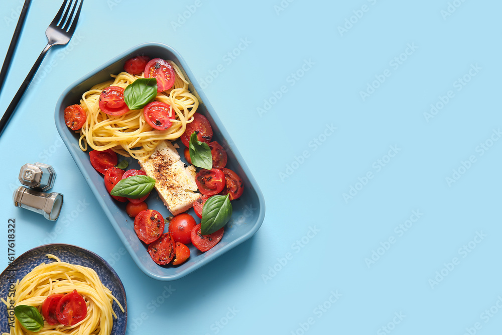 Baking dish of tasty pasta with tomatoes and feta cheese on blue background