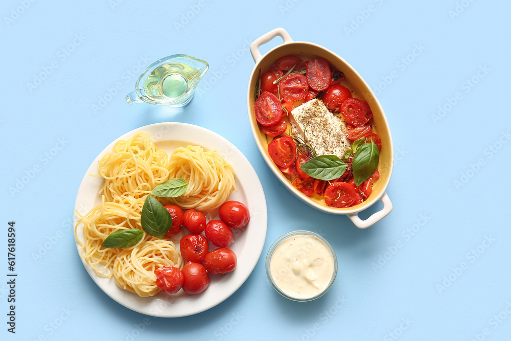 Baking dish with tasty tomatoes, feta cheese and pasta on blue background