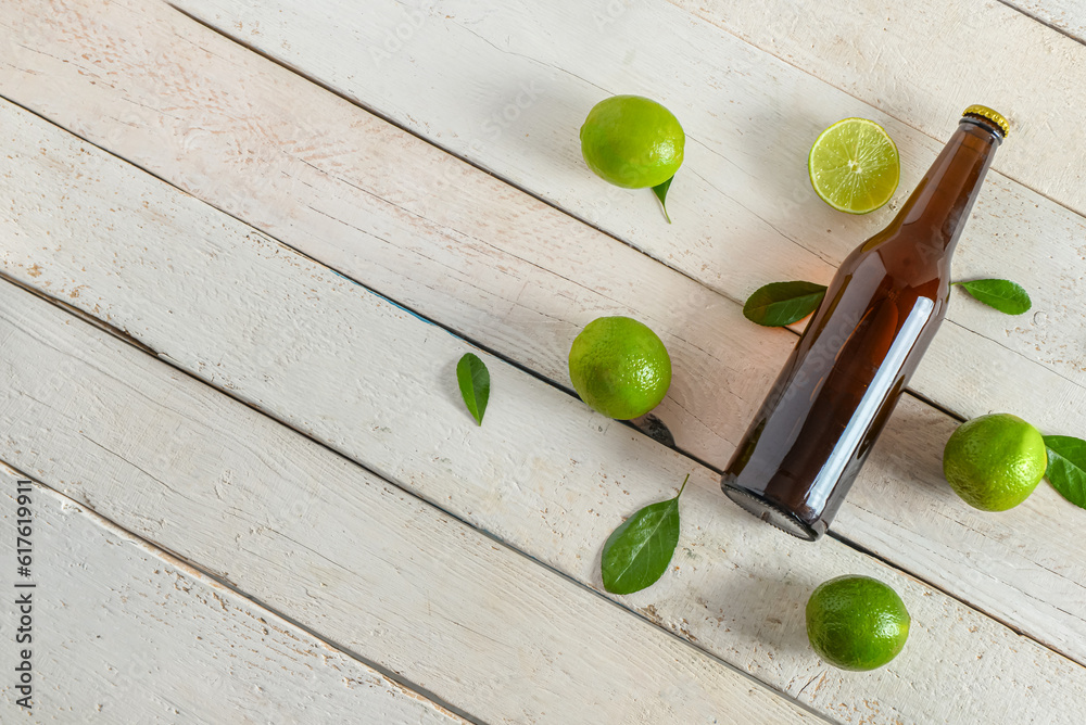 Bottle of cold beer with lime on light wooden background