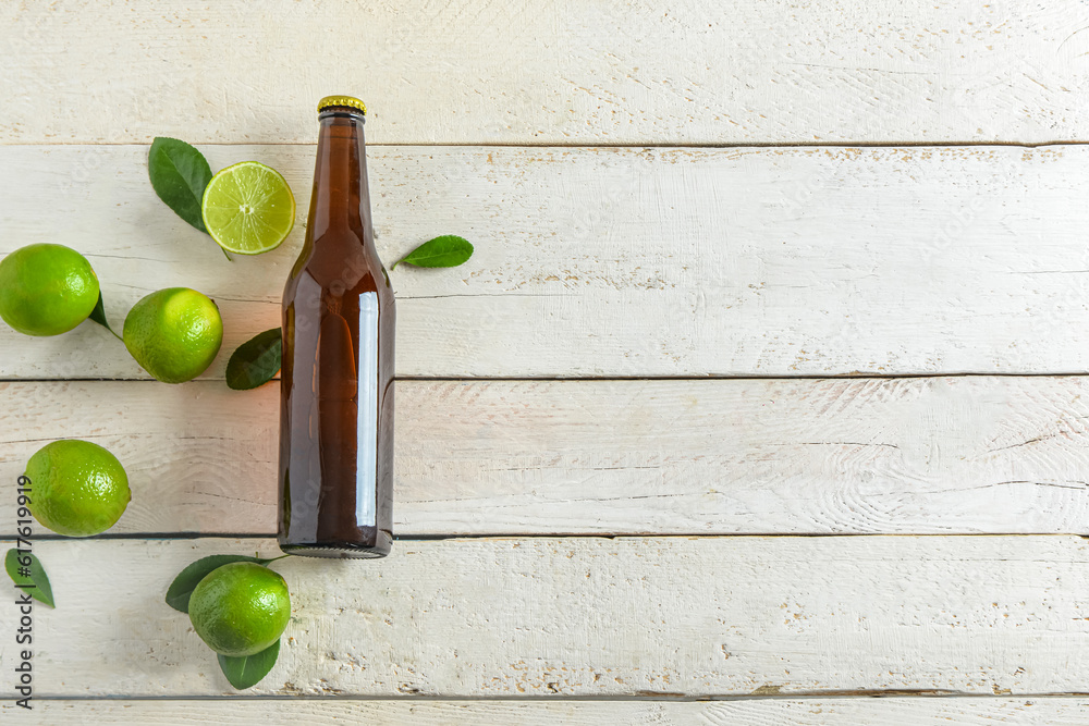 Bottle of cold beer with lime on light wooden background