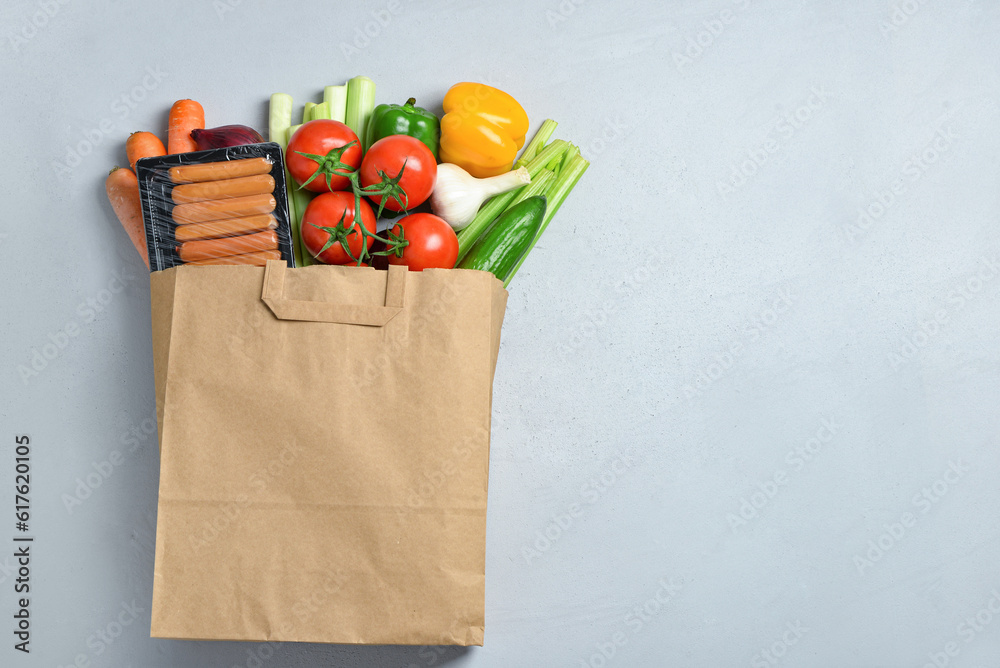 Paper bag with different products on grey background