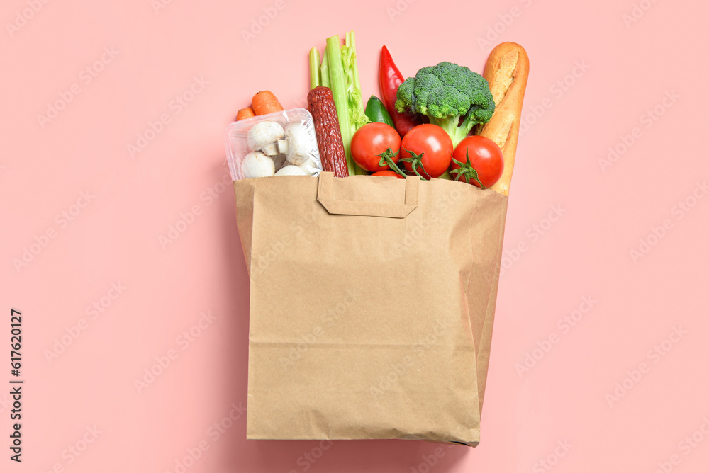 Paper bag with different products on pink background