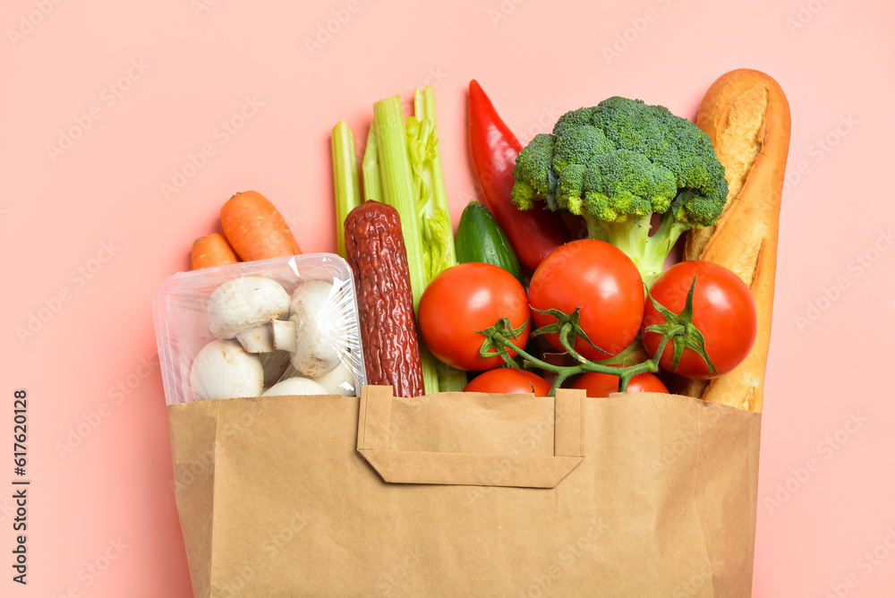 Paper bag with different products on pink background