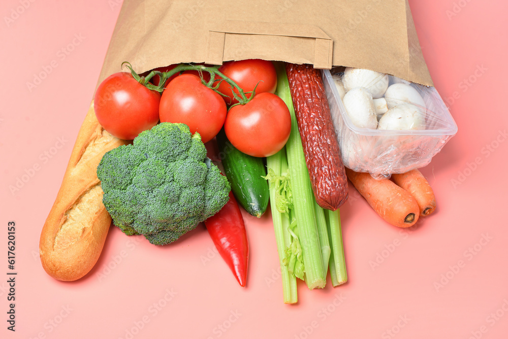 Paper bag with different products on pink background