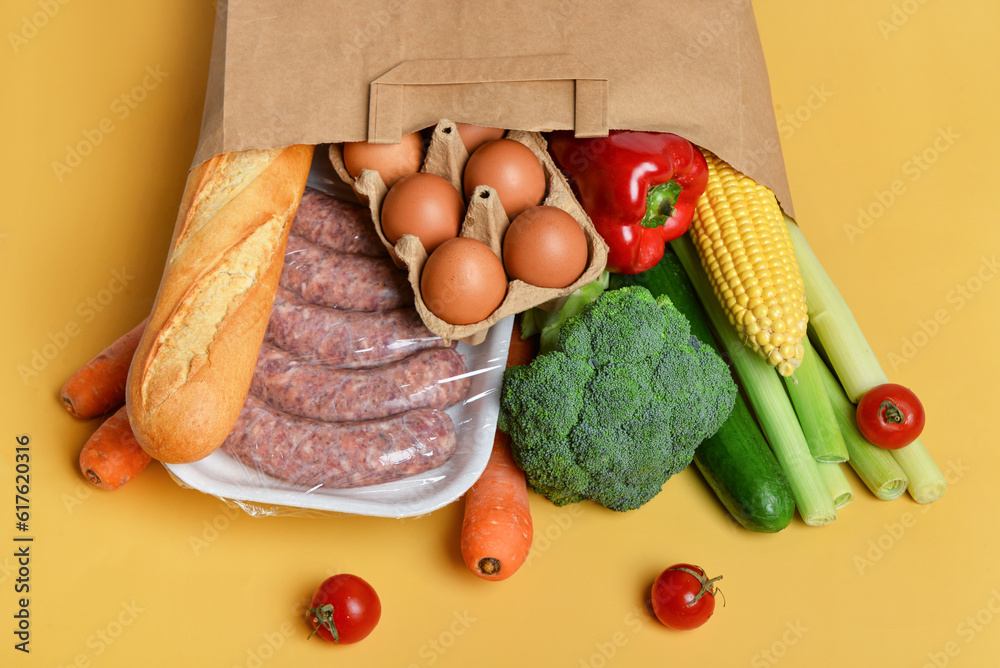 Paper bag with different products on yellow background