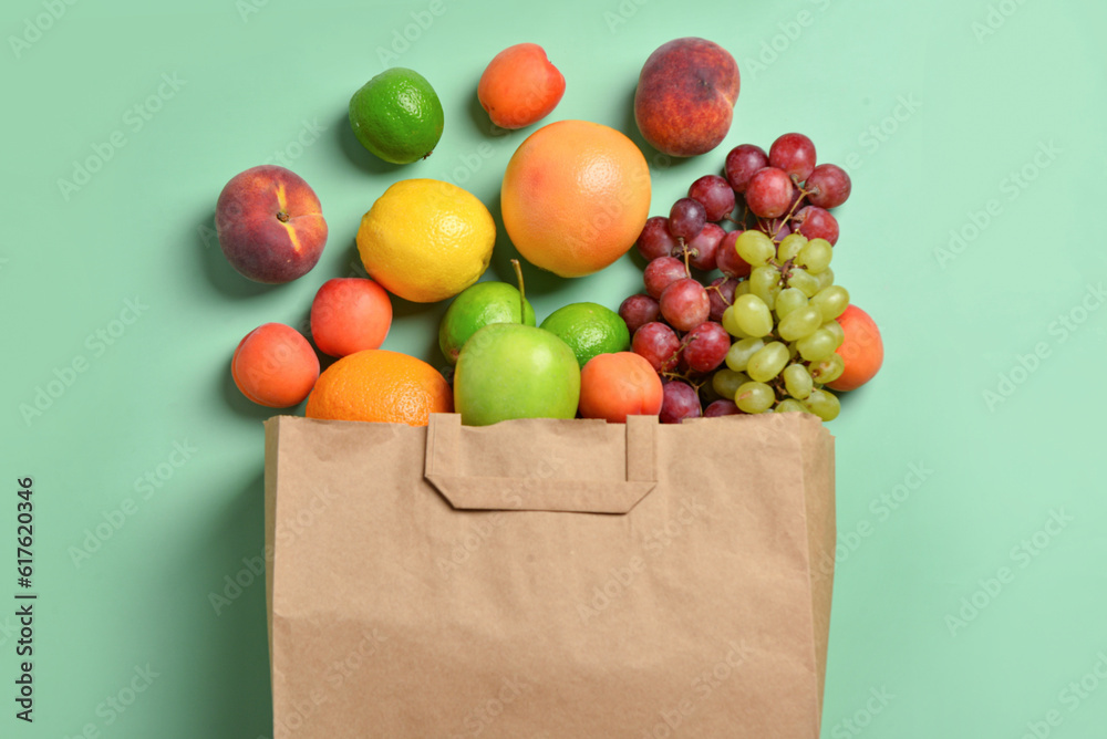 Paper bag with fresh fruits on turquoise background