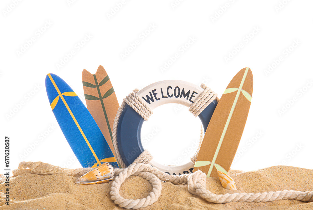 Mini surfboards with seashells and ring buoy on sand against white background