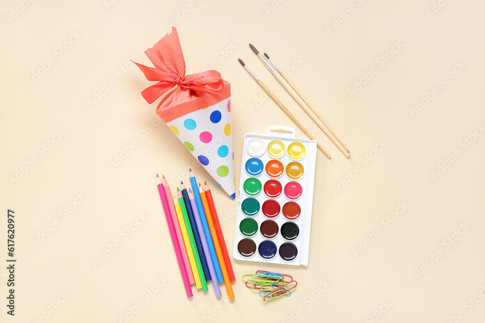 Red school cone with different stationery on pale orange background