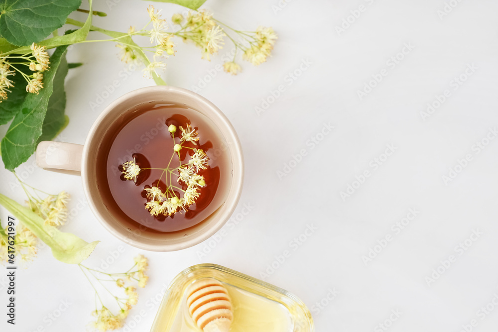 Cup of linden tea and bowl with honey on white table