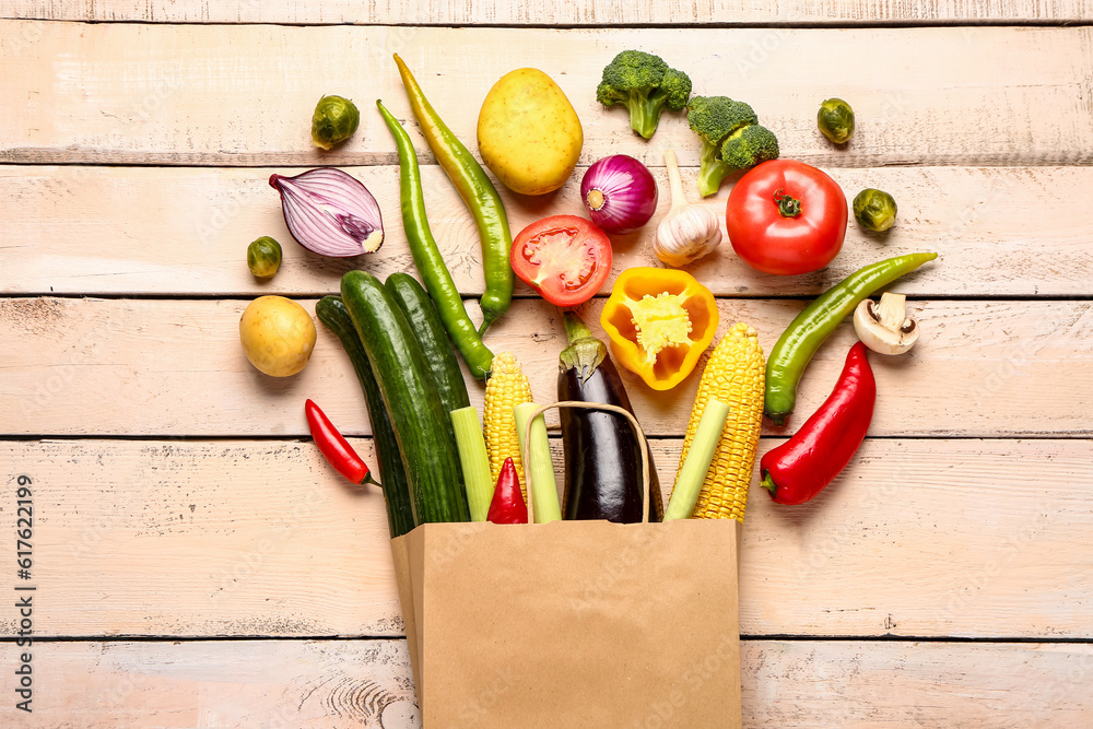 Package with fresh ripe vegetables on color wooden background