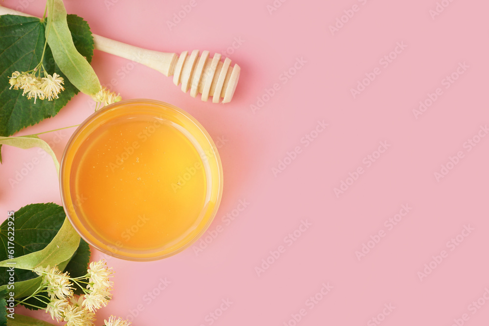 Glass bowl with linden honey and dipper on pink background