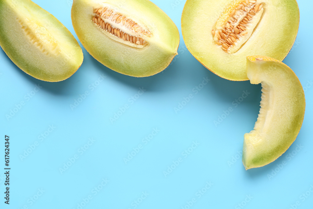 Half of sweet melon with pieces on blue background