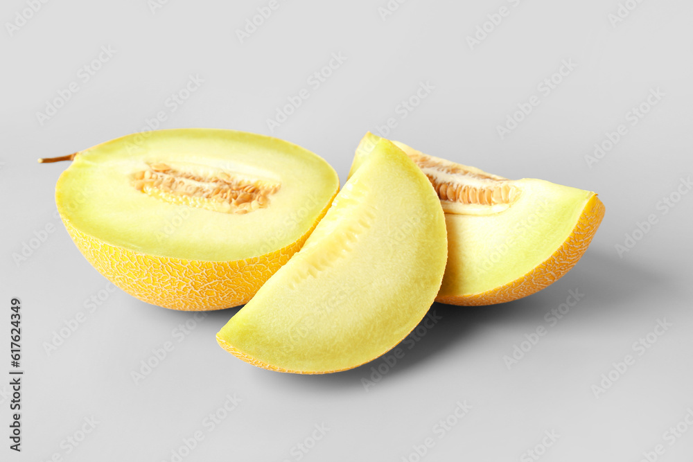 Half of sweet melon with pieces on grey background