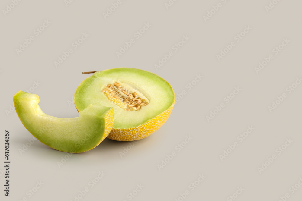 Half of sweet melon with piece on grey background