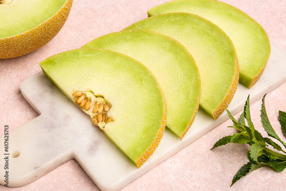 Board with pieces of sweet melon on pink background