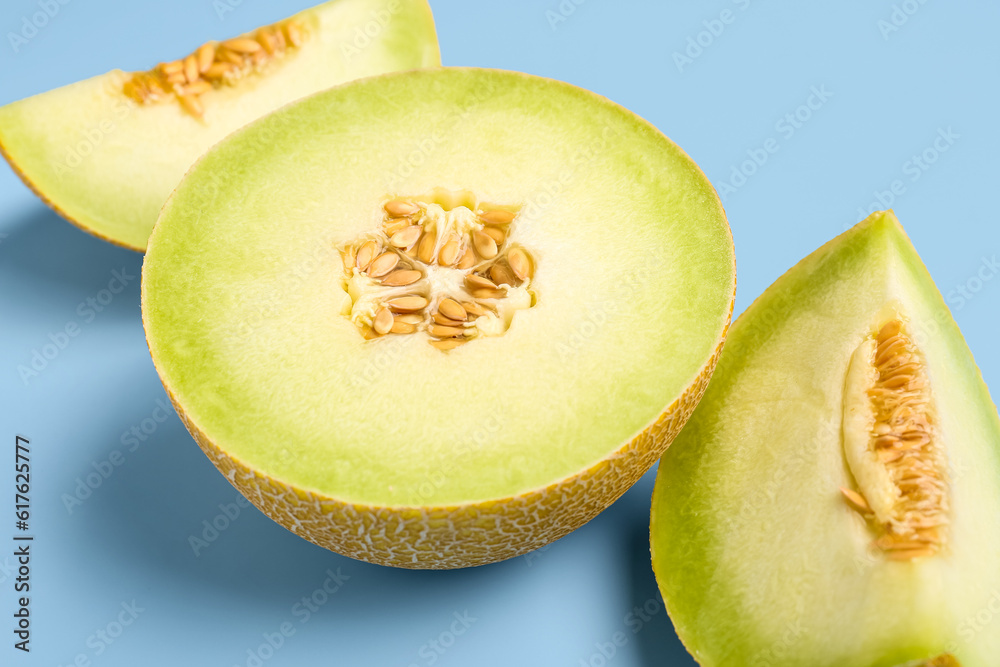 Half of sweet melon with pieces on blue background