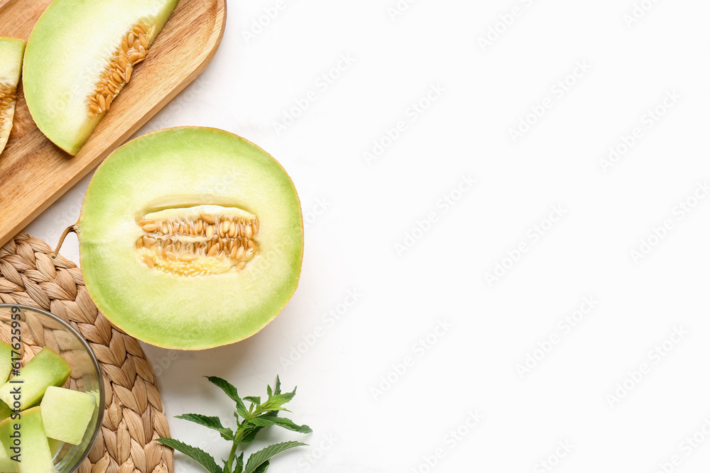 Half of sweet melon and wooden board with pieces on white background