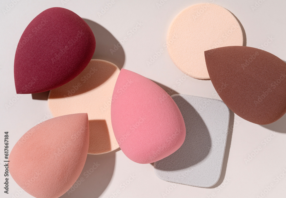 Multiple egg-shaped makeup sponges placed on a beige background.