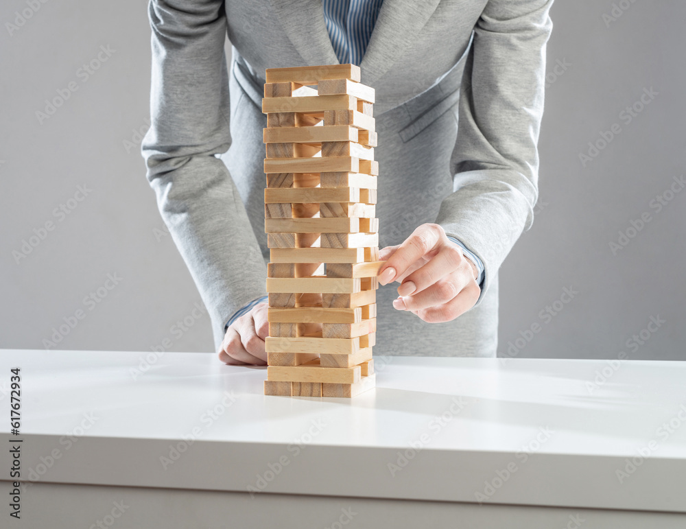 Businesswoman removing wooden block from tower