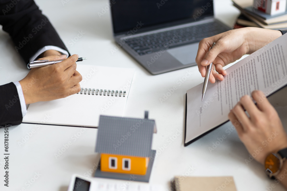 Real estate agent holding pen pointing at contract document for client to sign home purchase agreeme