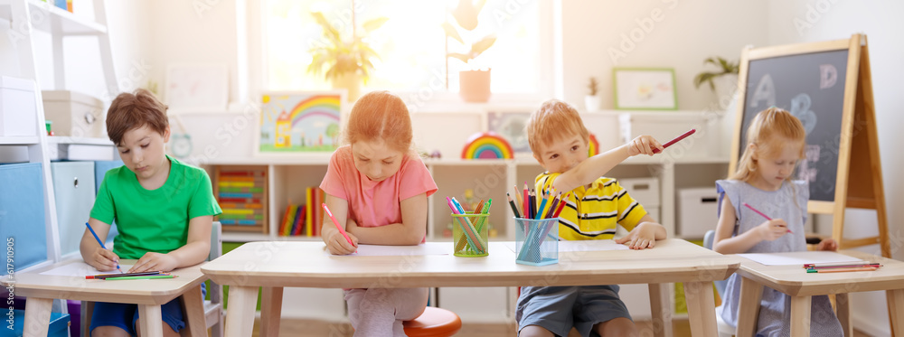 Group of children sitting in the classroom and drawing.