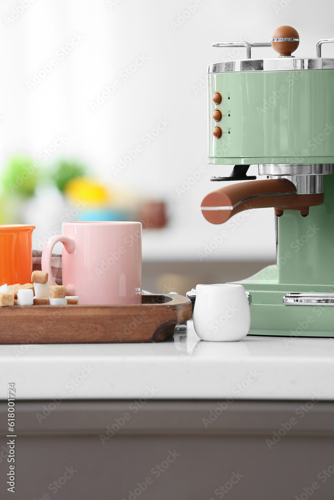 Modern coffee machine and cups of hot espresso on table in kitchen