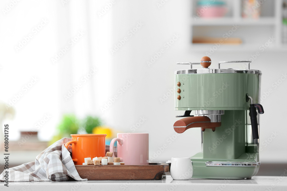 Modern coffee machine and cups of hot espresso on table in kitchen