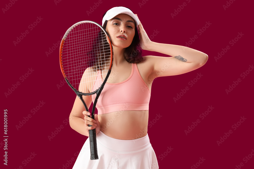 Young woman with tennis racket on pink background