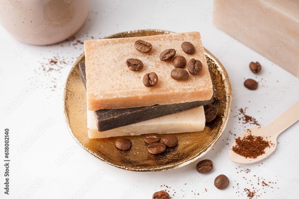 Plate with natural soap bars and coffee beans on light background