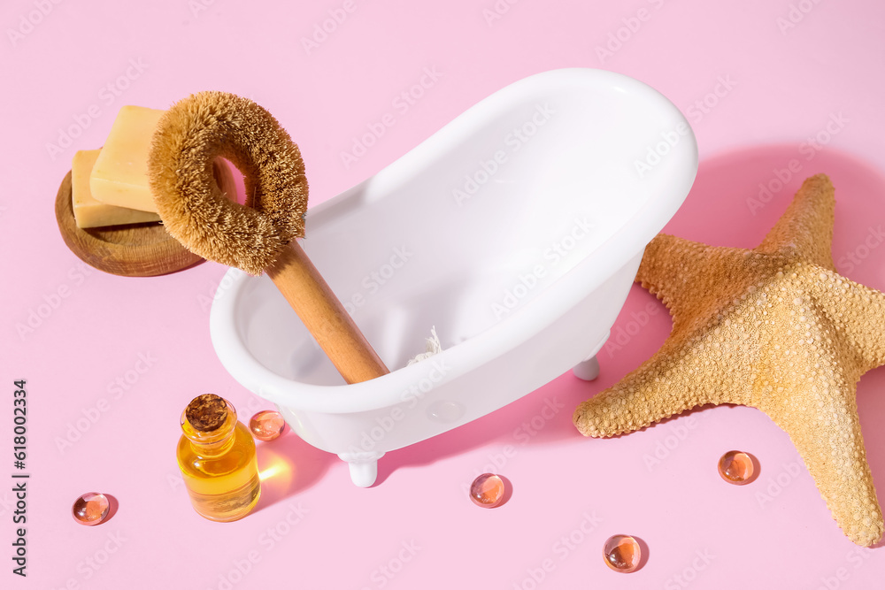 Small bathtub, bath supplies and starfish on pink background