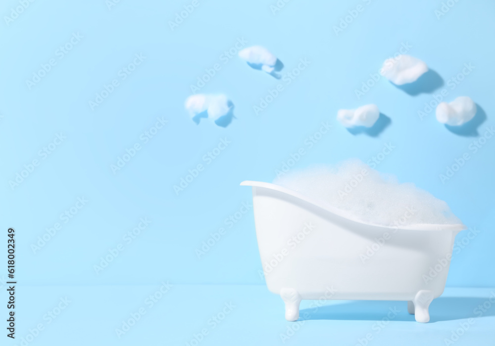 Composition with small bathtub and foam on color background