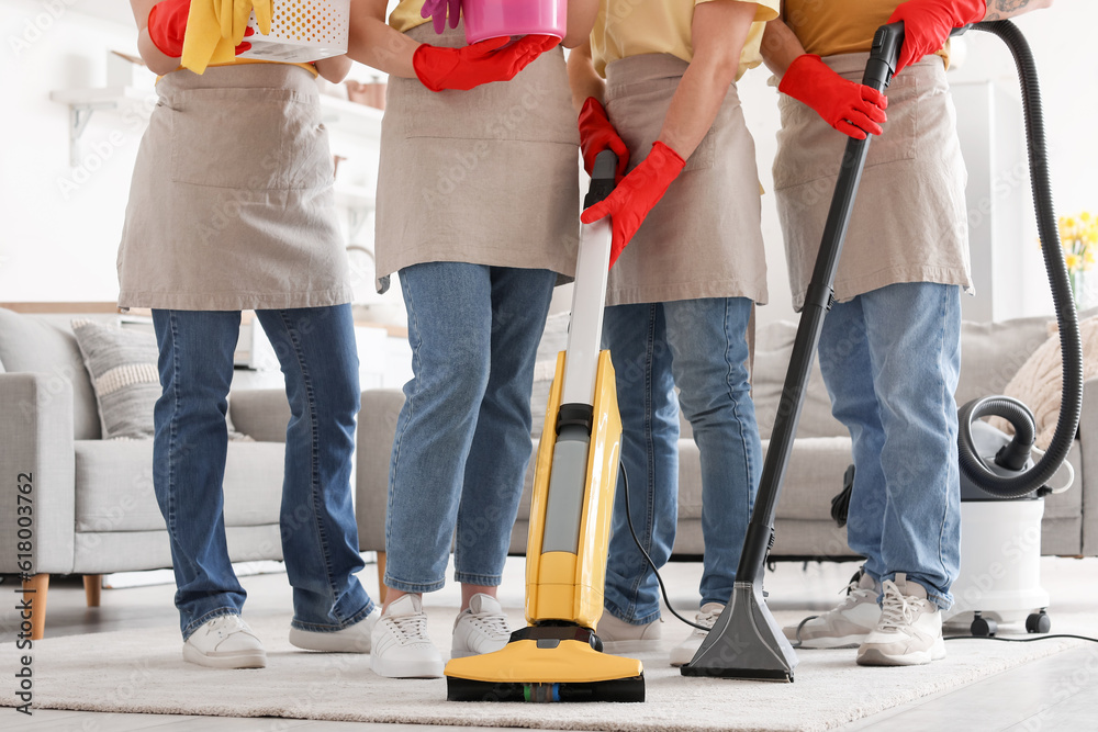 Young janitors with cleaning supplies in kitchen