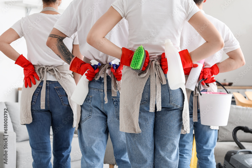 Young janitors with cleaning supplies in kitchen, back view