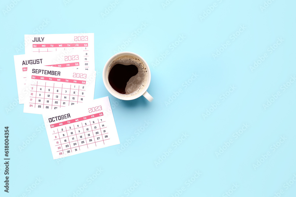 Pages of calendar and cup of coffee on blue background