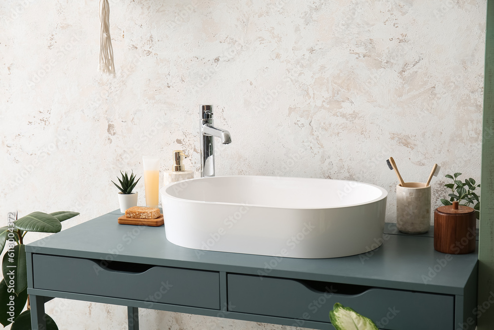 White sink with bath accessories on table in room