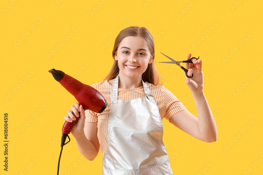 Female hairdresser with dryer and scissors on yellow background